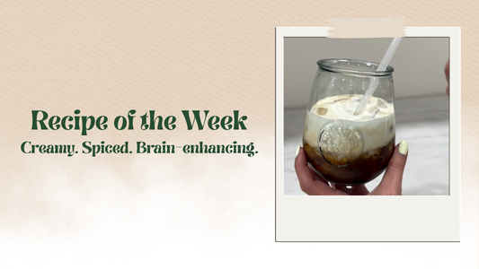 Iced glass of NeoBean Cerebro Cold Brew topped with whipped cinnamon cream and dusted with ground cinnamon, styled with coffee beans and cinnamon sticks on a wooden surface.